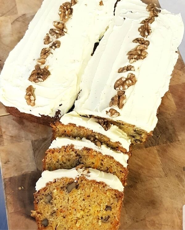 Carrot cake loaf topped with walnuts, sliced